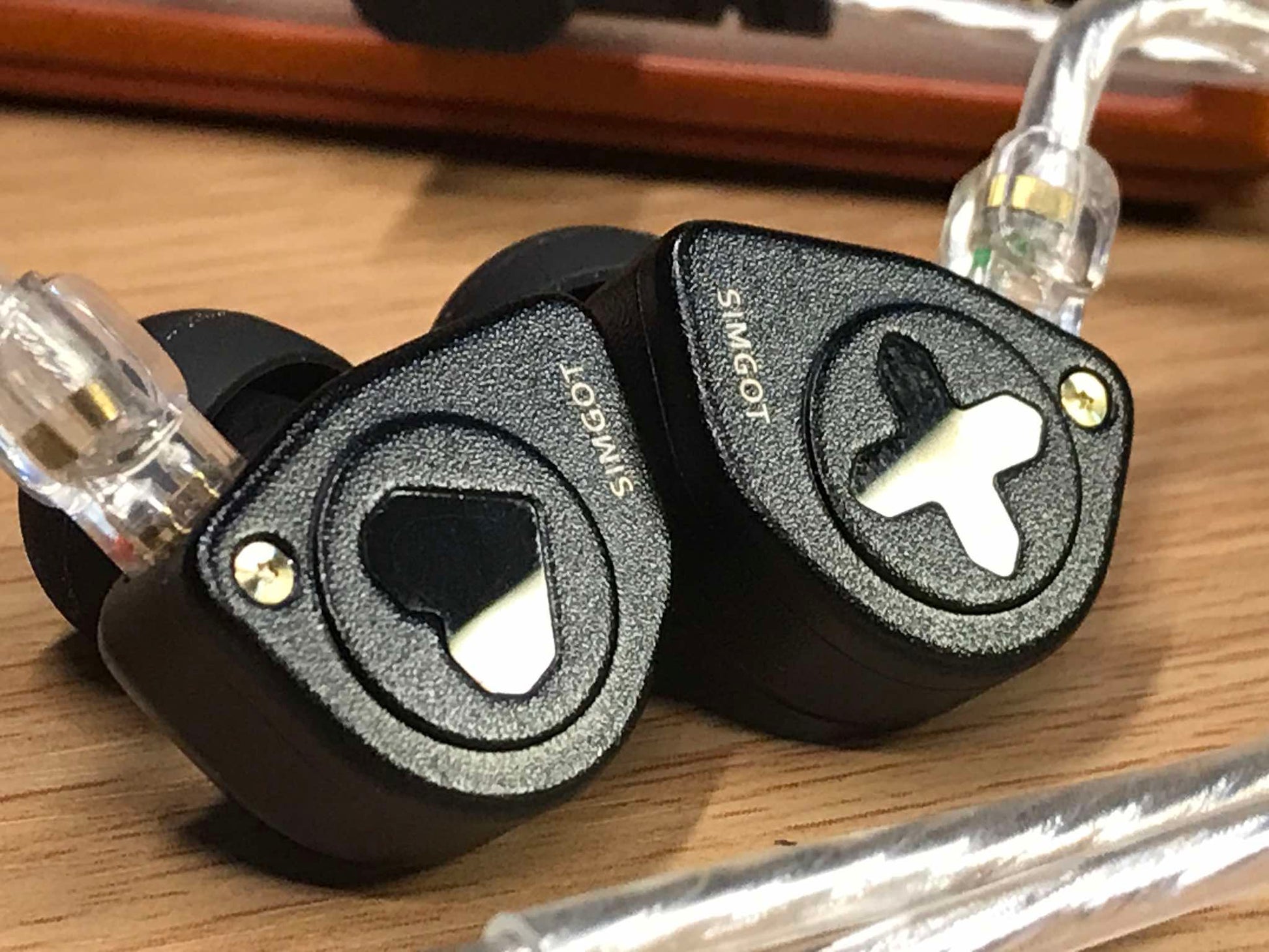Auriculares IEM SIMGOT EW300 Edición HBB con drivers tribrid: dinámico, planar y PZT, en uso con fondo neutro.