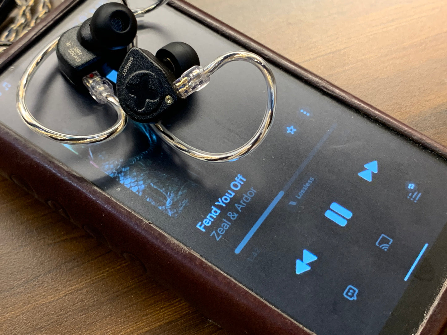 Auriculares IEM SIMGOT EW300 Edición HBB con drivers tribrid: dinámico, planar y PZT, en uso con cables y diseño en negro.