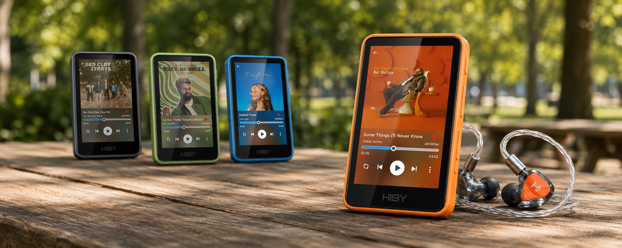 Smartphones displaying music streaming apps on a wooden table outdoors.