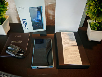 Reproductor de audio digital FIIO JM21 con pantalla Android 13 y Snapdragon 680, mostrando botones y puerto de auriculares.